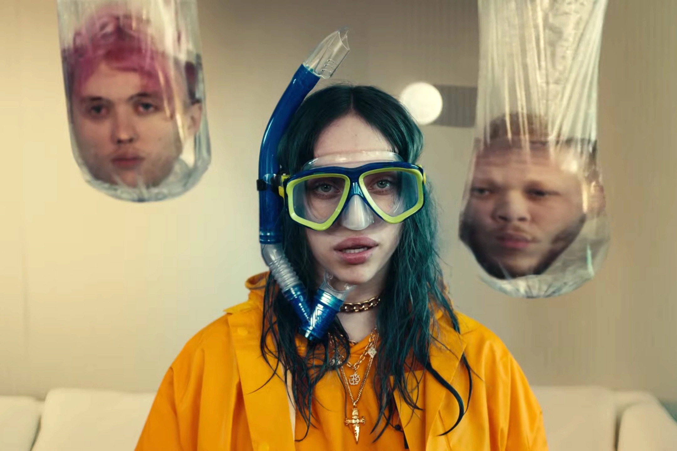 Billie Eilish portant un masque de plongée avec deux têtes coupées à ses côtés