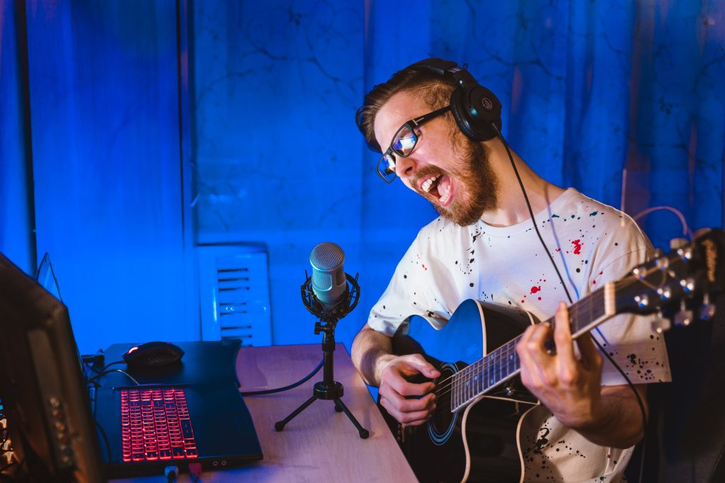 Un jeune homme en train de s'enregistrer en train de chanter et de jouer de la guitare